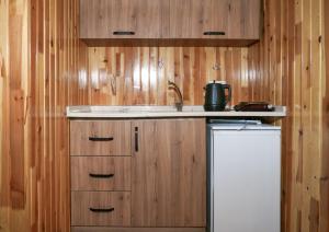 a kitchen with wooden walls and a sink and a refrigerator at Ruby Bungalow Alanya in Yaylalı