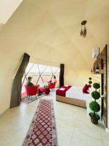 Un dormitorio con una cama y dos personas sentadas en sillas. en Wadi Rum Lana luxury camp, en Wadi Rum
