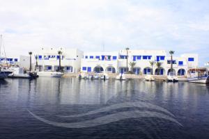 a boat in the water in front of a building at Marina Cap Monastir- Appart'Hôtel in Monastir