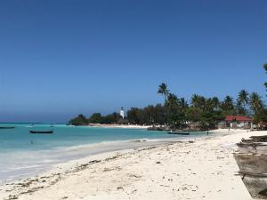 a beach with boats in the water and a lighthouse at Aluna Beach House Nungwi in Nungwi