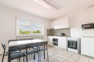 a kitchen with white cabinets and a table and chairs at Monteurapartment I 8 Betten I Küche I Waschmaschine I Balkon in Münster