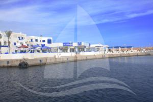 a reflection of a building in the water at Marina Cap Monastir- Appart'Hôtel in Monastir
