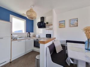 Cottage L'évasion des 2 caps-5 personnes- bord de mer في أودينجين: مطبخ فيه دواليب بيضاء وحائط ازرق