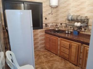 a kitchen with a white refrigerator and wooden cabinets at Appartement familial 3 in Oualidia