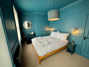 a small blue room with a bed and a mirror at ROOMS AT THE QUAYSIDE - stylish en-suite rooms on Poole Quay all fully refurbed in Poole