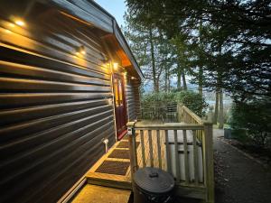 una veranda di una casa con porta in legno di LARCHES LODGE Norwegian log cabin, wood stove & spa a Church Stretton