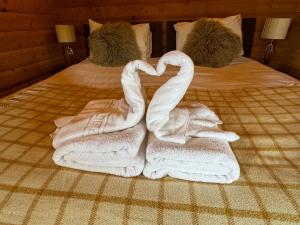 due cigni stanno creando una forma di cuore su un letto di LARCHES LODGE Norwegian log cabin, wood stove & spa a Church Stretton