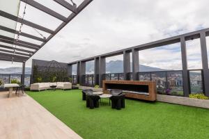 Un patio en la azotea con césped y muebles en un edificio. en XOE Designer Studio, en Quito