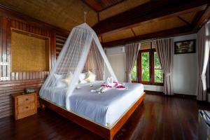 a bedroom with a bed with a mosquito net at Dusit Buncha Koh Tao by Riya Group in Ko Tao