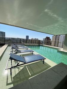 a pool with a bunch of lounge chairs on a building at Studio aconchegante I Perdizes I Nubank Parque in São Paulo