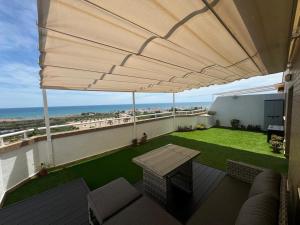 ein Balkon mit Tisch und großem Sonnenschirm in der Unterkunft Ático Amanecer Mediterráneo in Cabanes