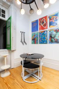 una mesa y dos taburetes en una habitación con pinturas en 14º Esquadra — Cais das Pedras Guest House, en Oporto