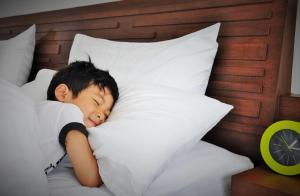 a little boy sleeping in a bed with a pillow at Family House Zen Boutique Resort in Pai