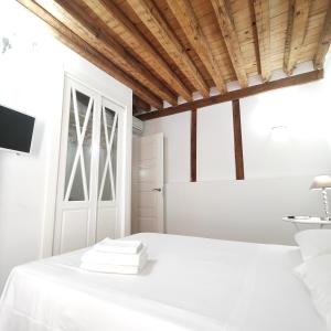 een witte slaapkamer met een bed en een houten plafond bij Apartamento Tres Culturas Lux in Toledo
