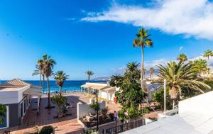 Blick auf einen Strand mit Palmen und das Meer in der Unterkunft Oceanfront Apartment Parque Santiago II in Playa de las Americas