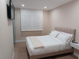 Schlafzimmer mit einem weißen Bett und einem Flachbild-TV in der Unterkunft Pensión Vázquez in Vimianzo