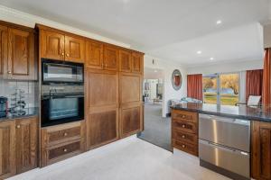 a kitchen with wooden cabinets and stainless steel appliances at Mount Pisa Lake View in Cromwell