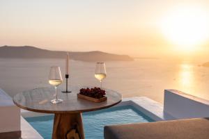 a table with two glasses of wine and a bowl of fruit at Villa Lukas in Imerovigli