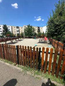 une clôture en bois avec une aire de jeux dans un parc dans l'établissement Davinci Apartment, à Sibiu