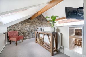 a room with a stone wall and a table and a chair at 4 Beckside Cottage in Windermere