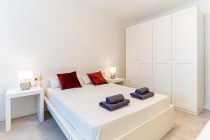 a white bedroom with a large white bed with red pillows at TrendyHomes City Center in Almería