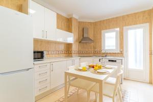 a kitchen with white cabinets and a table and chairs at TrendyHomes City Center in Almería