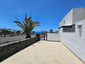 a white building with a fence and a palm tree at Luna Azul in Playa Blanca