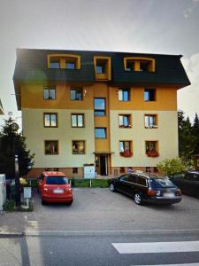 a building with two cars parked in a parking lot at Apartmán Dorian in Bešeňová