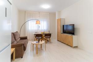 a living room with a couch a table and a television at TrendyHomes City Center in Almería