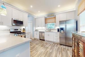 a kitchen with white cabinets and stainless steel appliances at The Salty Whale in Galveston