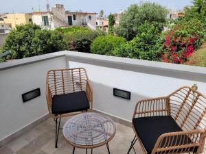 two chairs and a glass table on a balcony at Cozy Corner Apartment Forio in Forio d'Ischia
