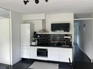 a kitchen with white cabinets and a black tile wall at In Almere, Close to Amsterdam in Almere