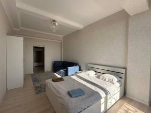 a bedroom with a bed and a blue chair at Centrum Residence apartment on Turusbekova 9 in Bishkek