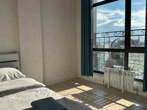 a bedroom with a bed and a large window at Centrum Residence apartment on Turusbekova 9 in Bishkek