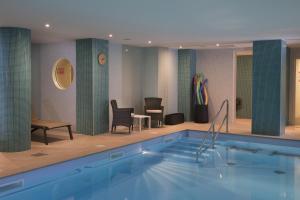 a swimming pool in a hotel with chairs and a table at Domitys Les Dunes D'argent in Saint-Cyprien