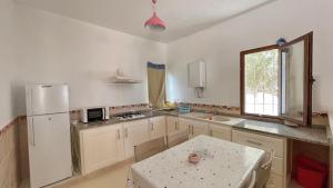 a kitchen with a table and a white refrigerator at Sweet Villa Residence in Houmt Souk +1 photo