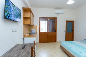 a room with a bed and a desk and a television at Hotel Olti in Vlorë