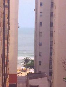 a view of the beach from between two buildings at Quarto Privativo - Pitangueiras - 50mts da Praia in Guarujá