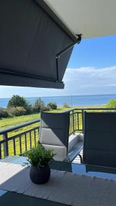 a porch with a chair and a table with a view of the ocean at Daria’s Luxury Apartment-the hidden gem in Epanomi