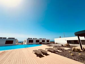 a swimming pool with lounge chairs next to a building at Julia Ancor beach in Abades