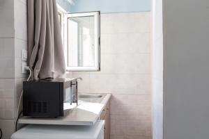 a bathroom with a television on a counter with a sink at Theo Apartment Rethymno in Rethymno