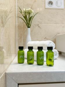 Tres botellas verdes sobre un mostrador en un baño. en Comfy Stay Apartment, en Trenčín