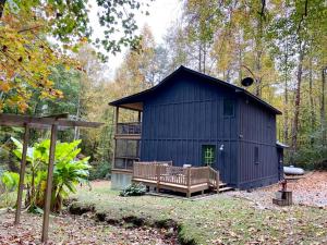 ein schwarzes Gebäude mit einer Terrasse im Wald in der Unterkunft Close to Lake Blue Ridge, Hot Tub, Swing Beds in Morganton