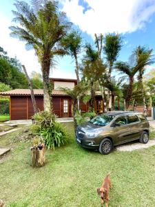 a car parked in front of a house with a dog at Chale Joia da Serra 3,5 do Centro de Campos do Jordão - Completo in Campos do Jordão