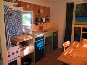 een keuken met een wastafel, een fornuis en een tafel bij Woonwagen Wadkovice in Pieterburen