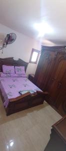 a bedroom with a bed with purple sheets and a lamp at فيلا ترى البحر بقرية أندلسية مطروح بالتكييفات in Marsa Matruh