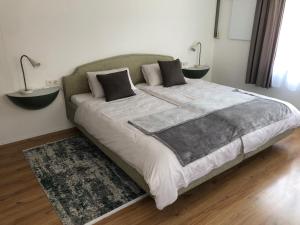 a large bed in a bedroom with two lamps at Ursprungshaus - Nuss und Traube in Dornbirn