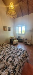 una camera da letto con un letto e un lampadario di Monte das Romas a Charnequinha
