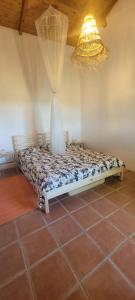 un letto in una camera con lampadario a braccio di Monte das Romas a Charnequinha