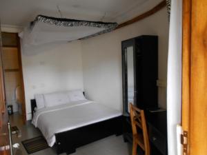 a small bedroom with a bed and a mirror at Chel & Vade Hotel in Jinja
